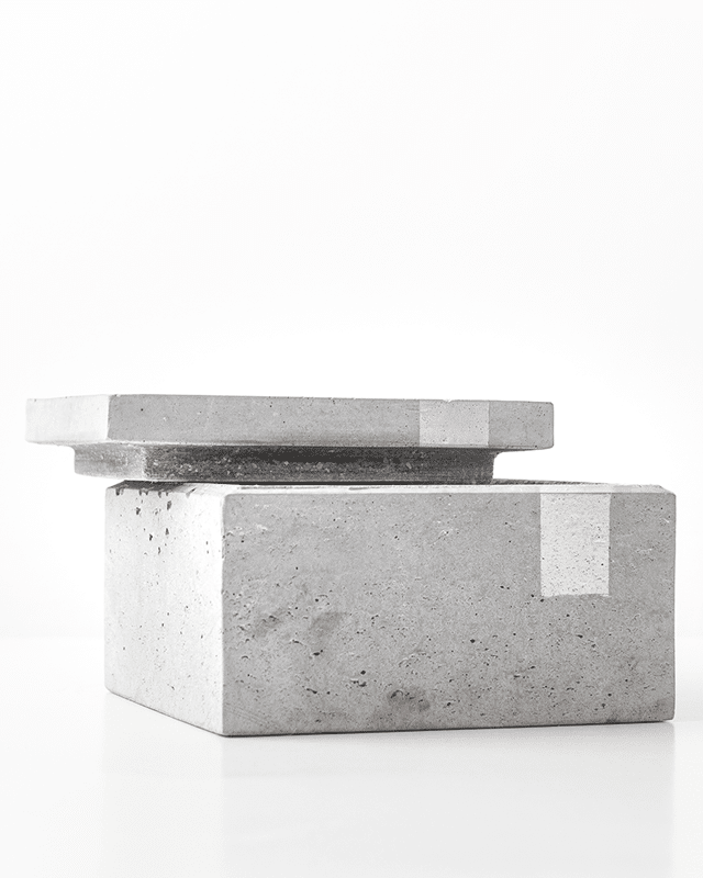 Halványszürke beton ékszerdoboz ezüst mintával és félig nyitott tetővel.